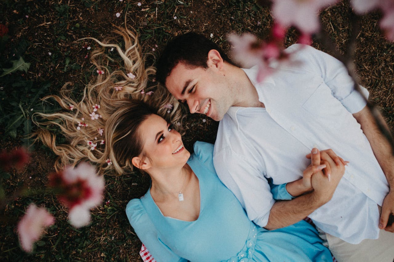 A joyous couple lying on the ground amid blooming flowers, symbolizing love and romance.